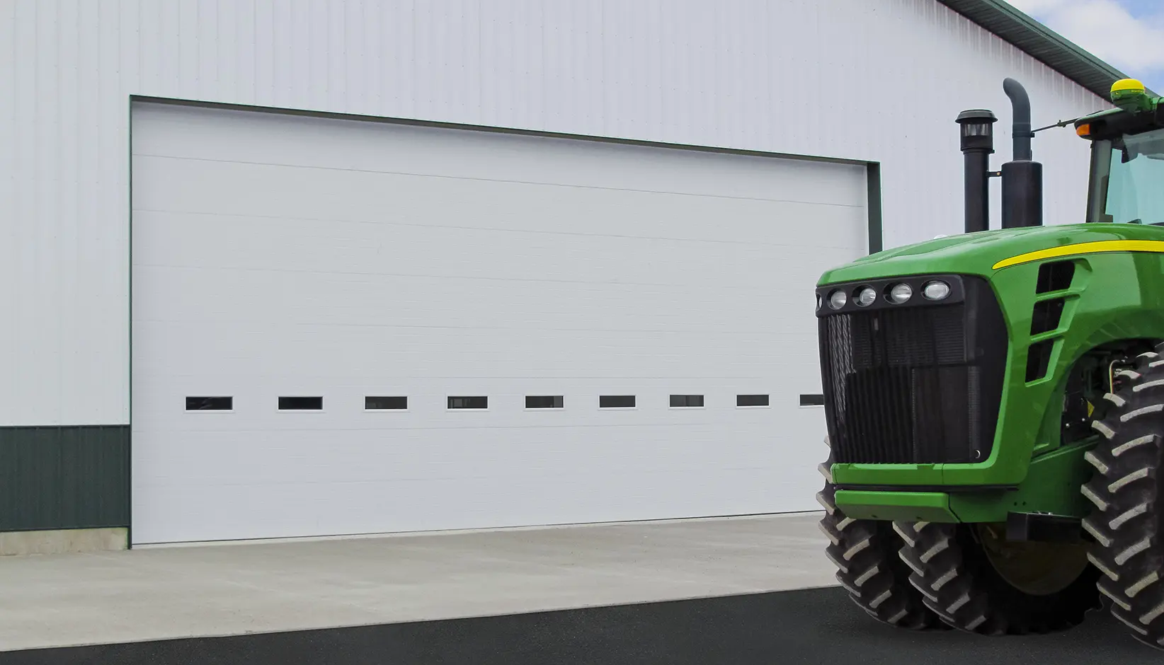 White Energy Series overhead sectional doors with a tractor beside it.