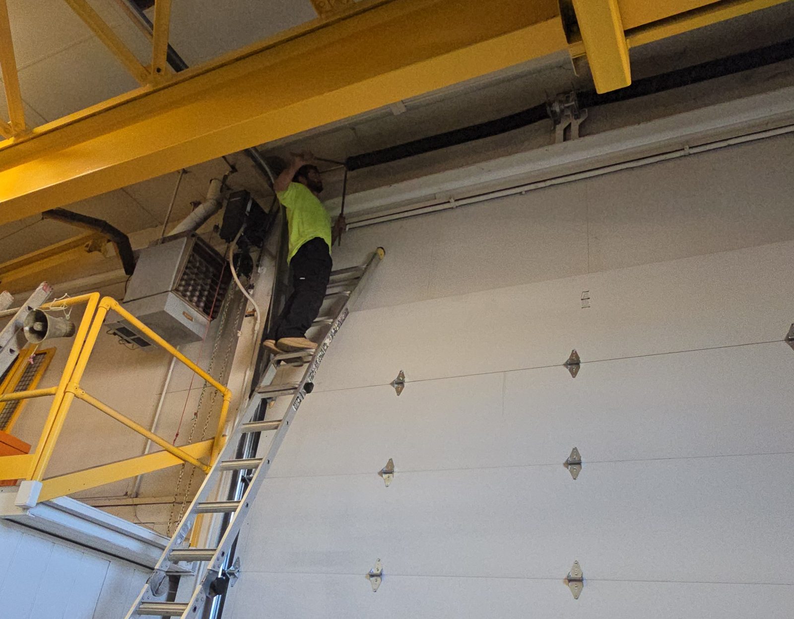 Technician on a ladder servicing a commercial overhead door
