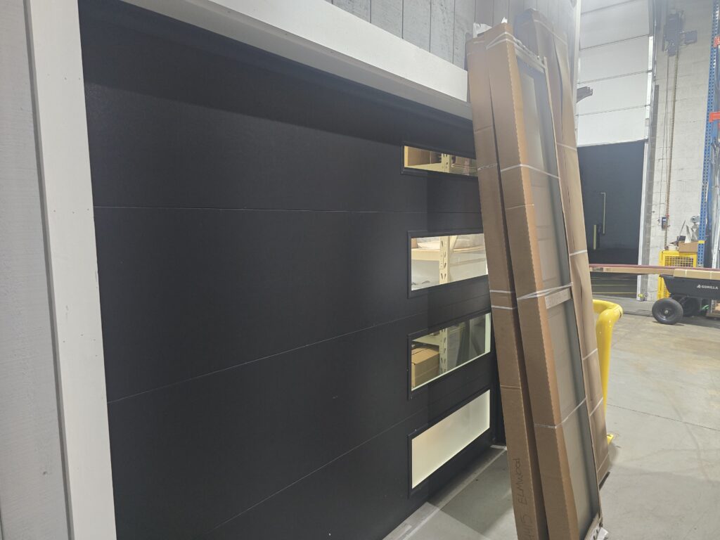 Black modern garage door with a row of windows on display at Proactive Garage Door Repair