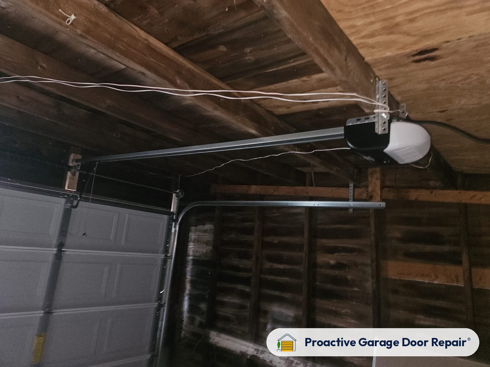 Garage door opener mounted in an older garage with a wood ceiling