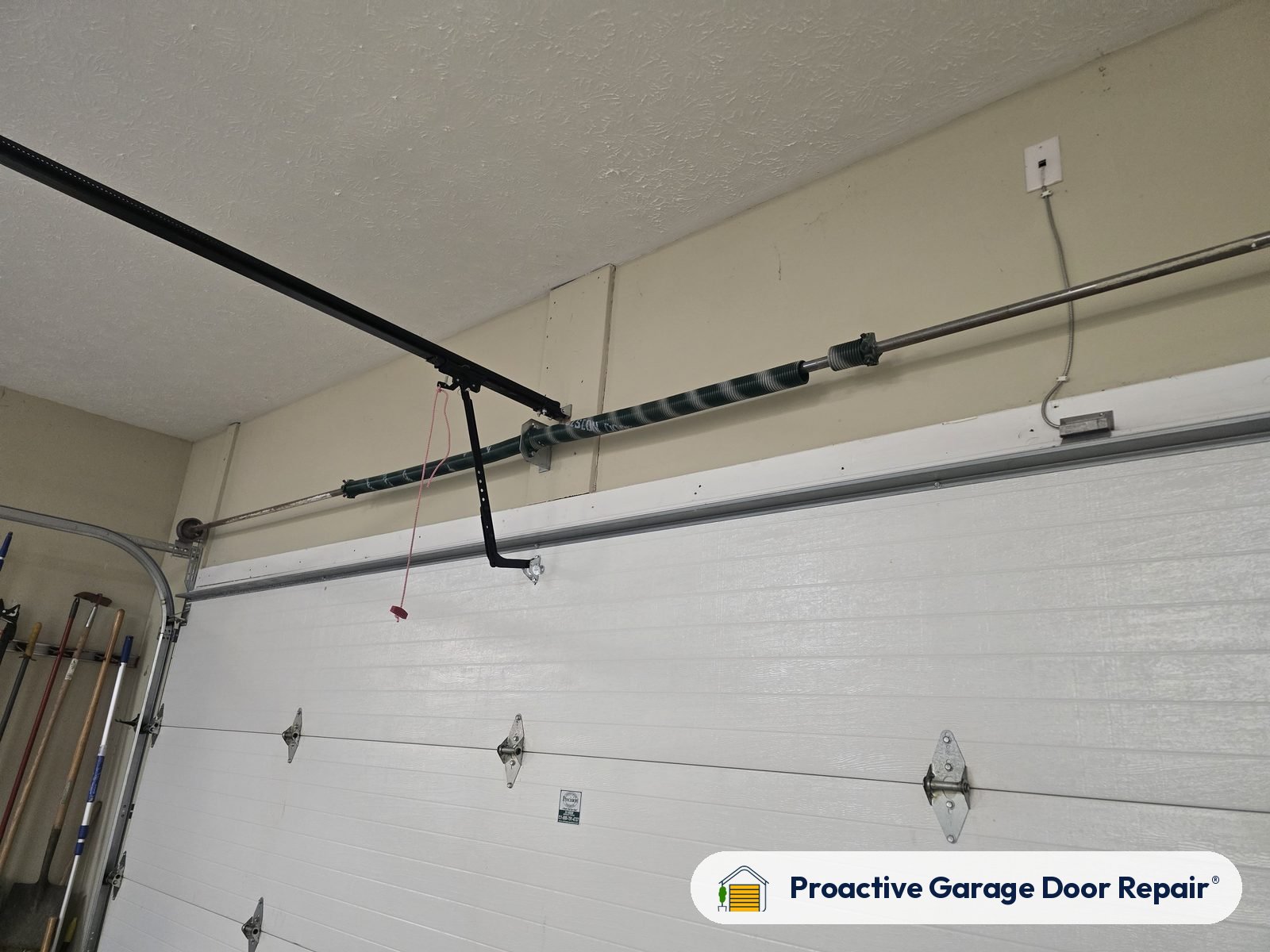 Torsion spring and opener rail above a white garage door
