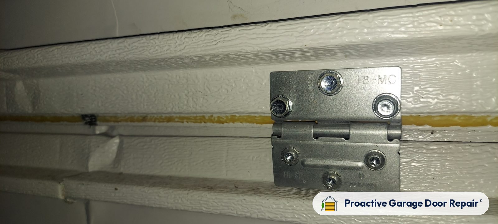 Close-up of a hinge on a white steel garage door
